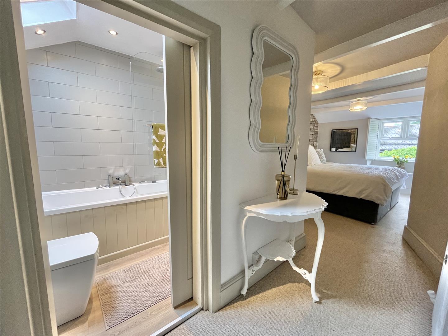 Master bedroom with exposed stone feature wall and fitted wardrobes