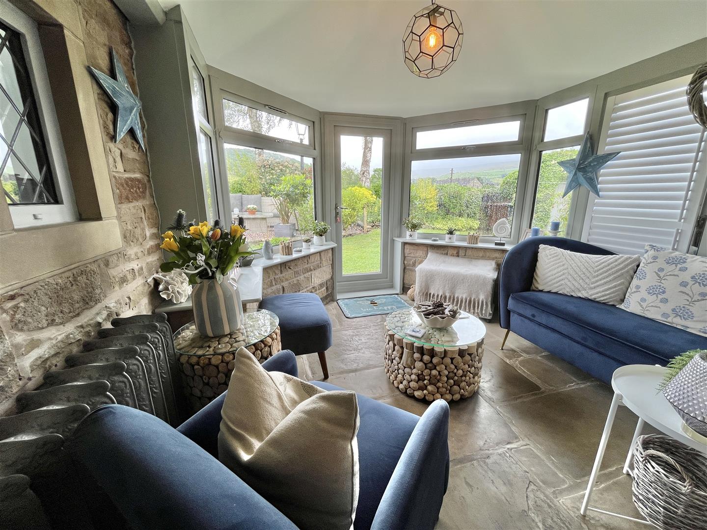 Cottage conservatory with stone floor and a wide view onto a green garden