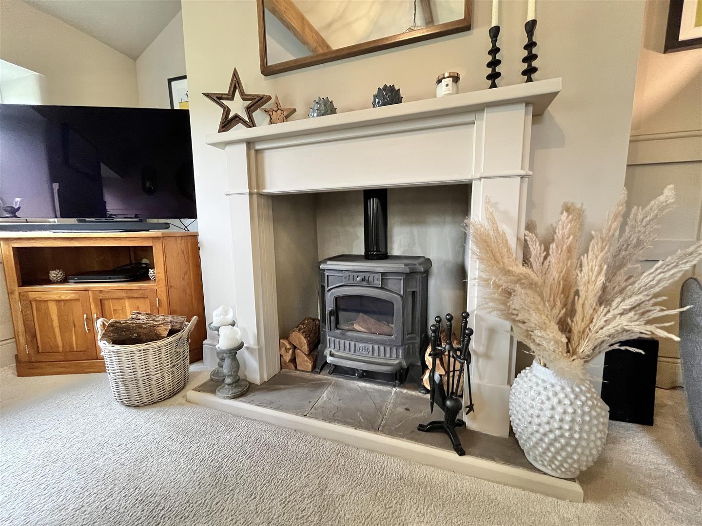 Vaulted first-floor lounge with timber beams and a wood-burning stove